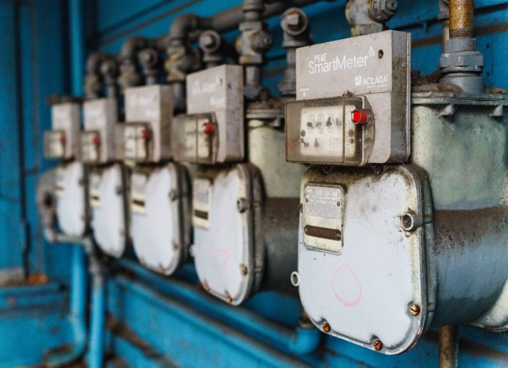 Multiple smart utility meters lined up on a blue industrial wall.